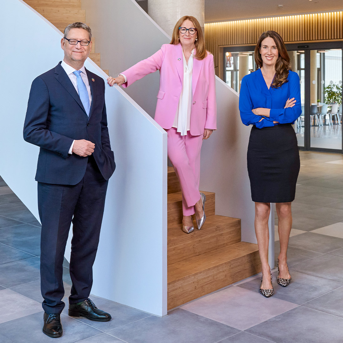 Foto: Ein Mann mit Anzug und Krawatte steht zwischen zwei elegant gekleideten Frauen.